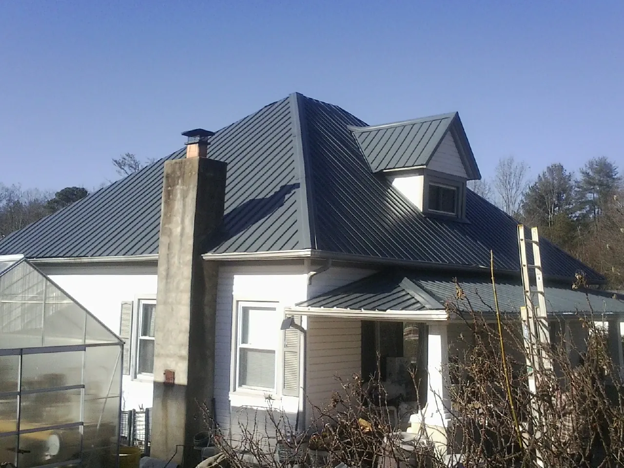 Dark blue standing seam metal roof on a white farmhouse with dormer — Slate & Tile Roof Repair by Roofing Brothers in East Bend