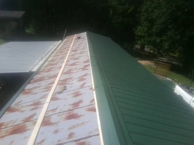Old rusted panels beside newly installed green metal roofing — Wind Damage Roof Repair by Roofing Brothers in East Bend