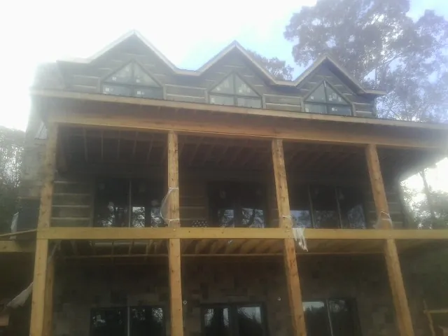 Dormers and porch framing on a large log home under construction — Roof Coating work by our crew in East Bend