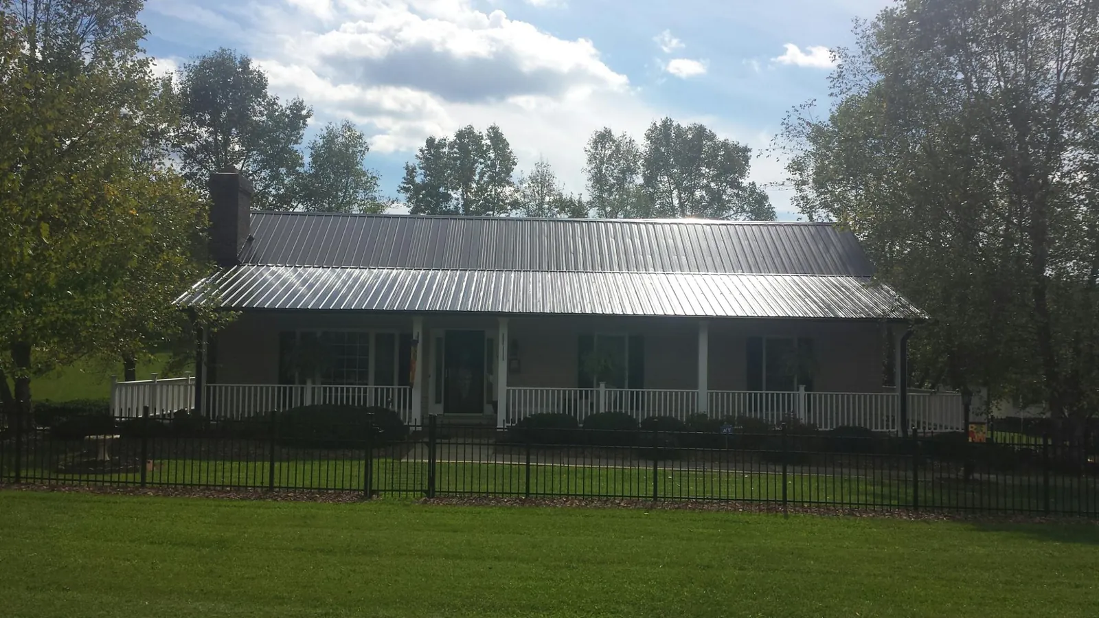 Gray metal roof on a brick ranch with a full width front porch — Gutter Guard Installation work by our crew in East Bend