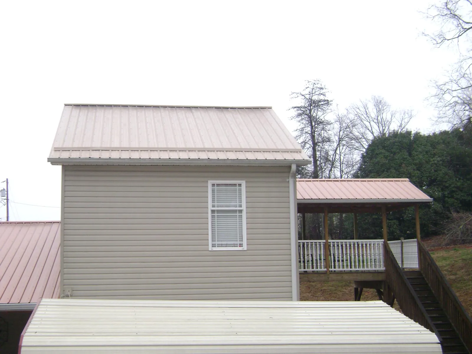 Tan metal roofs on a two story addition and attached porch, from a Roof Replacement job in East Bend