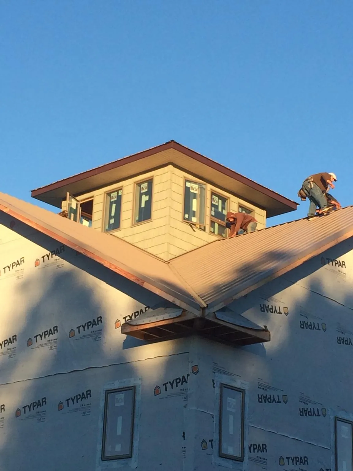 Roofers working around a rooftop cupola on a new metal roof at sunset — Roof Waterproofing in East Bend by Roofing Brothers